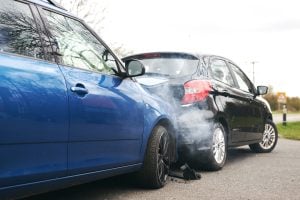 Two cars involved in traffic accident on side of the road.