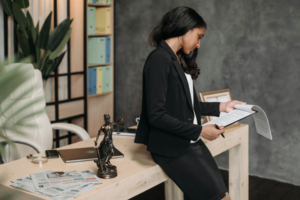 Woman lawyer reviewing documents in office, leaning on desk.