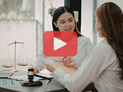 Two women in a meeting on a lawyers office. Red play buttom overlay and SEC logo.