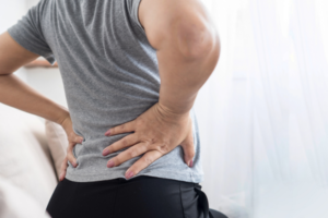 Person holding their back, showing pain or discomfort.