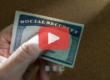 Person holding social security card. Red play buttom overlay and SEC logo.