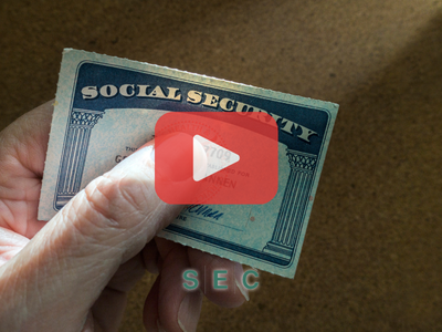 Person holding social security card. Red play buttom overlay and SEC logo.